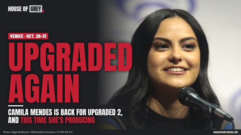 Camila Mendes smiling at a microphone in a striped sweater at WonderCon