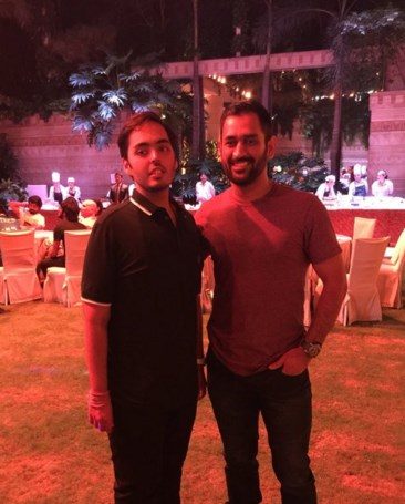 Anant Ambani and MS Dhoni standing side by side at an evening event