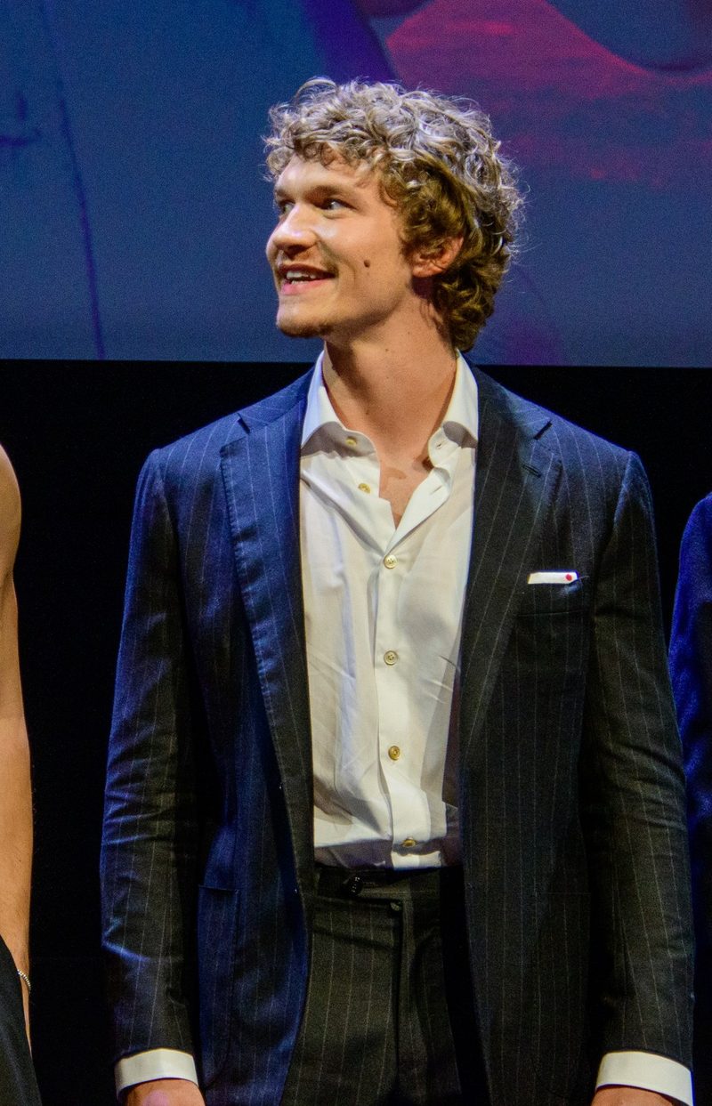 Connor Storrie in a navy suit and open-collar shirt at a premiere