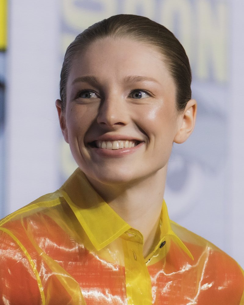 Hunter Schafer smiling in a sheer yellow and orange collared shirt at San Diego Comic-Con