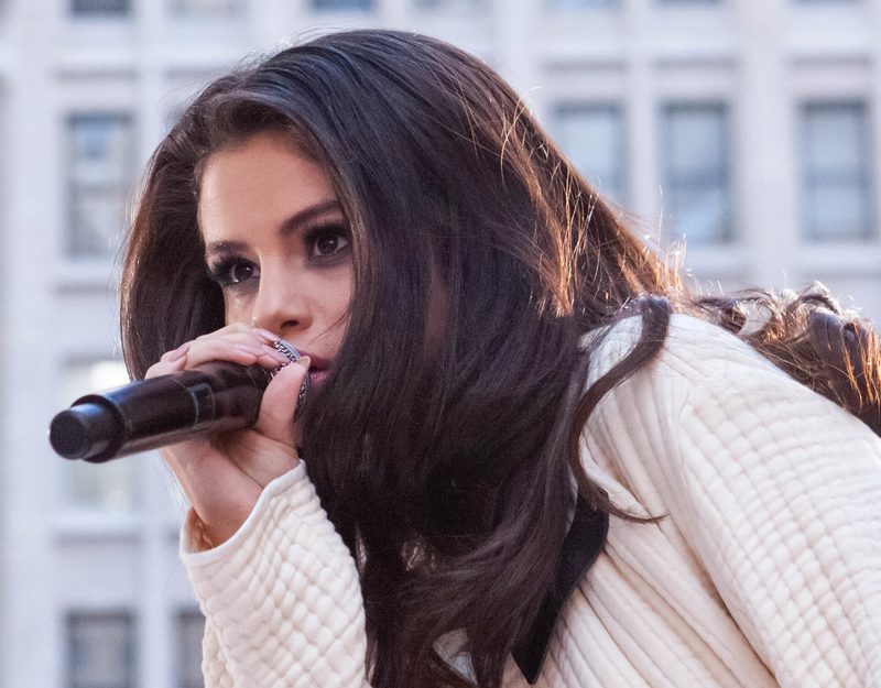 Selena Gomez singing into a microphone on stage in New York