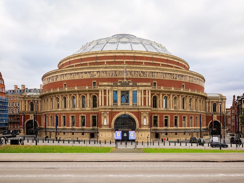 The round red-brick Royal Albert Hall with its glass-and-iron dome under a cloudy sky